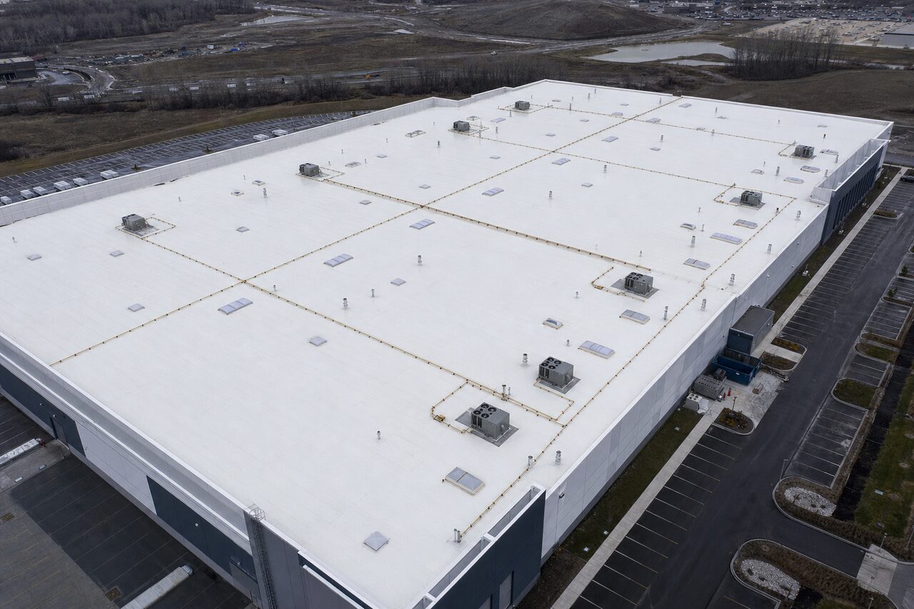 Industrial metal roof coating sealing the rusting seams and fasteners of a large standing-seam plant roof